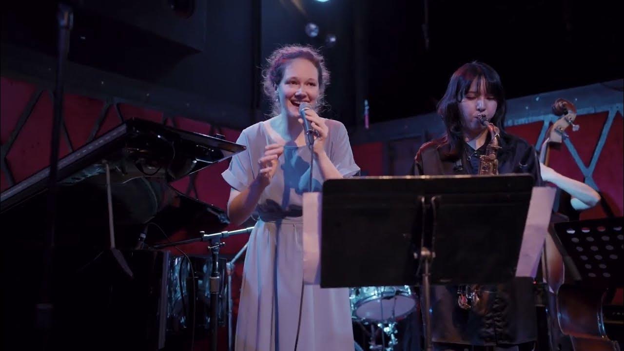 Embedded video: Tabea singing on stage, next to her Hina Oikawa blowing on alto sax